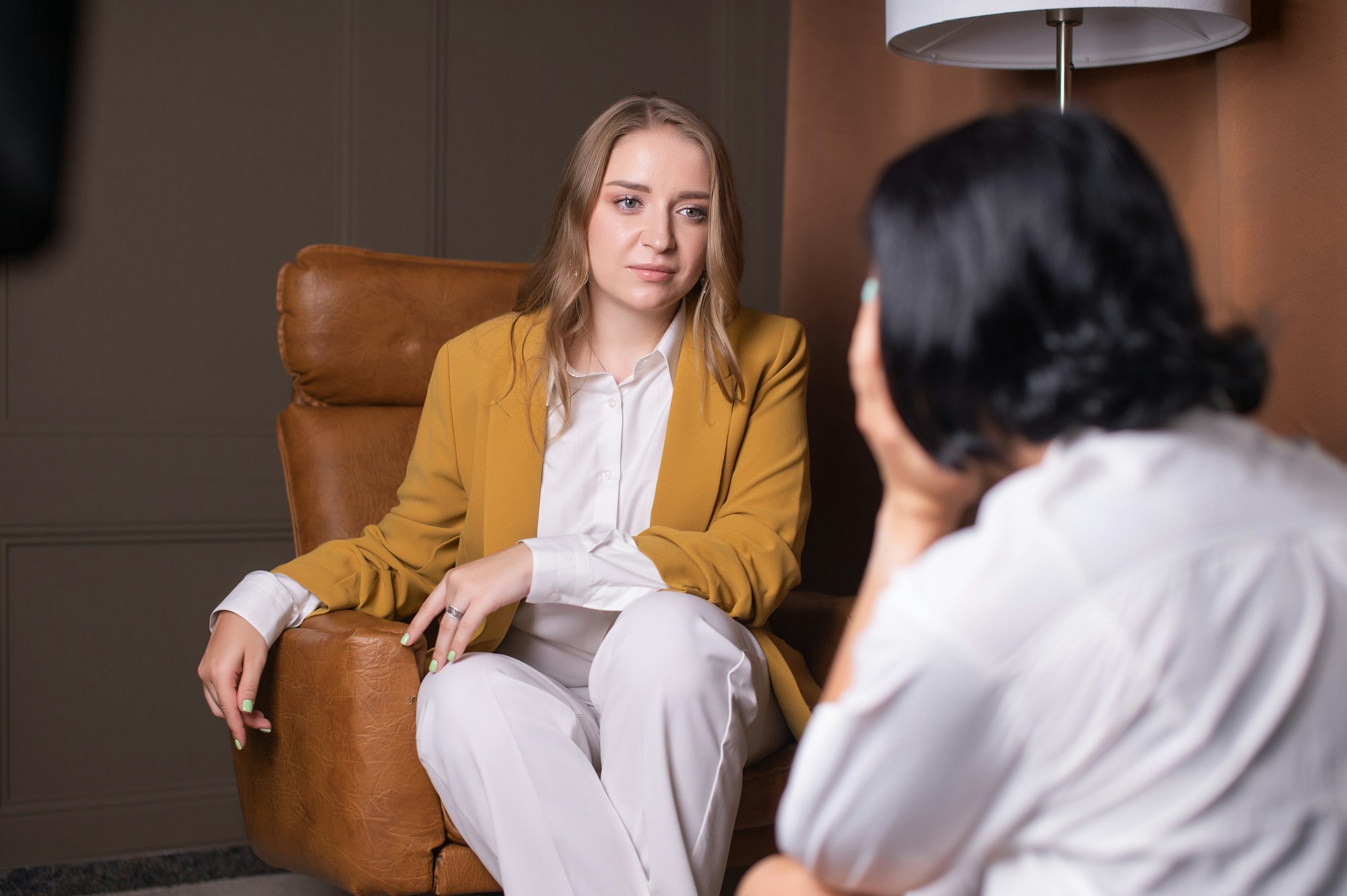 A psychologist girl listens to a client sitting in an armchair